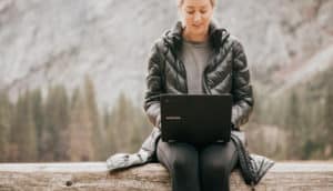 Woman sitting on log with laptop